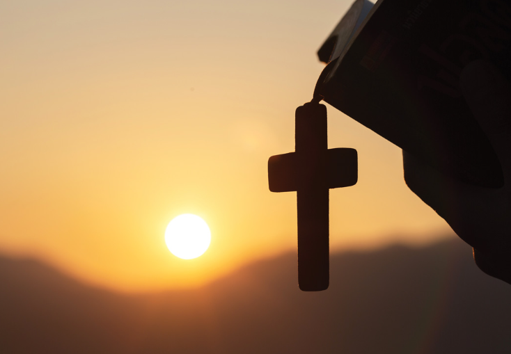 a cross with a sun in the background