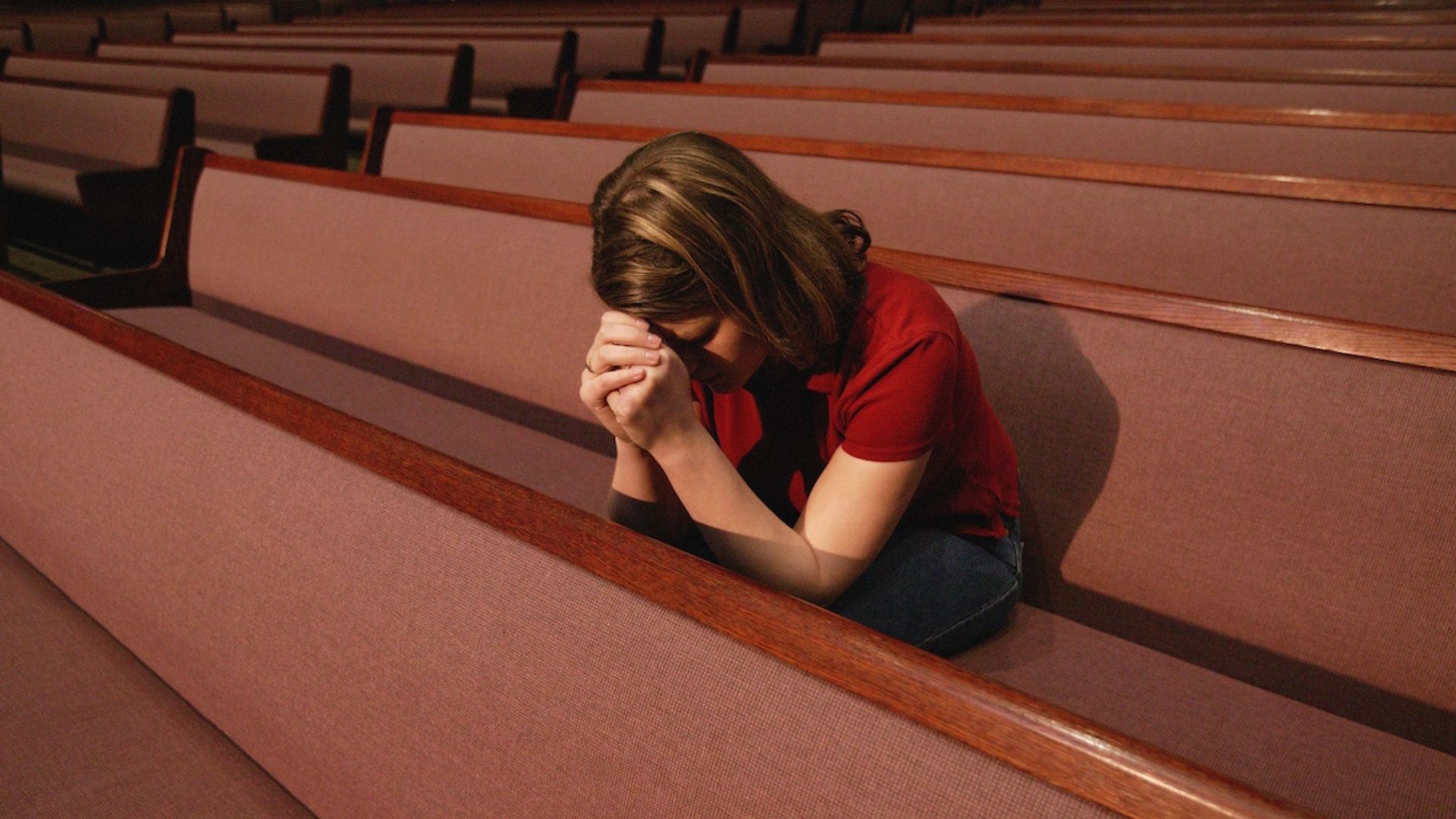 a lady sitting in a church with benches showing the impact of religion on mental health