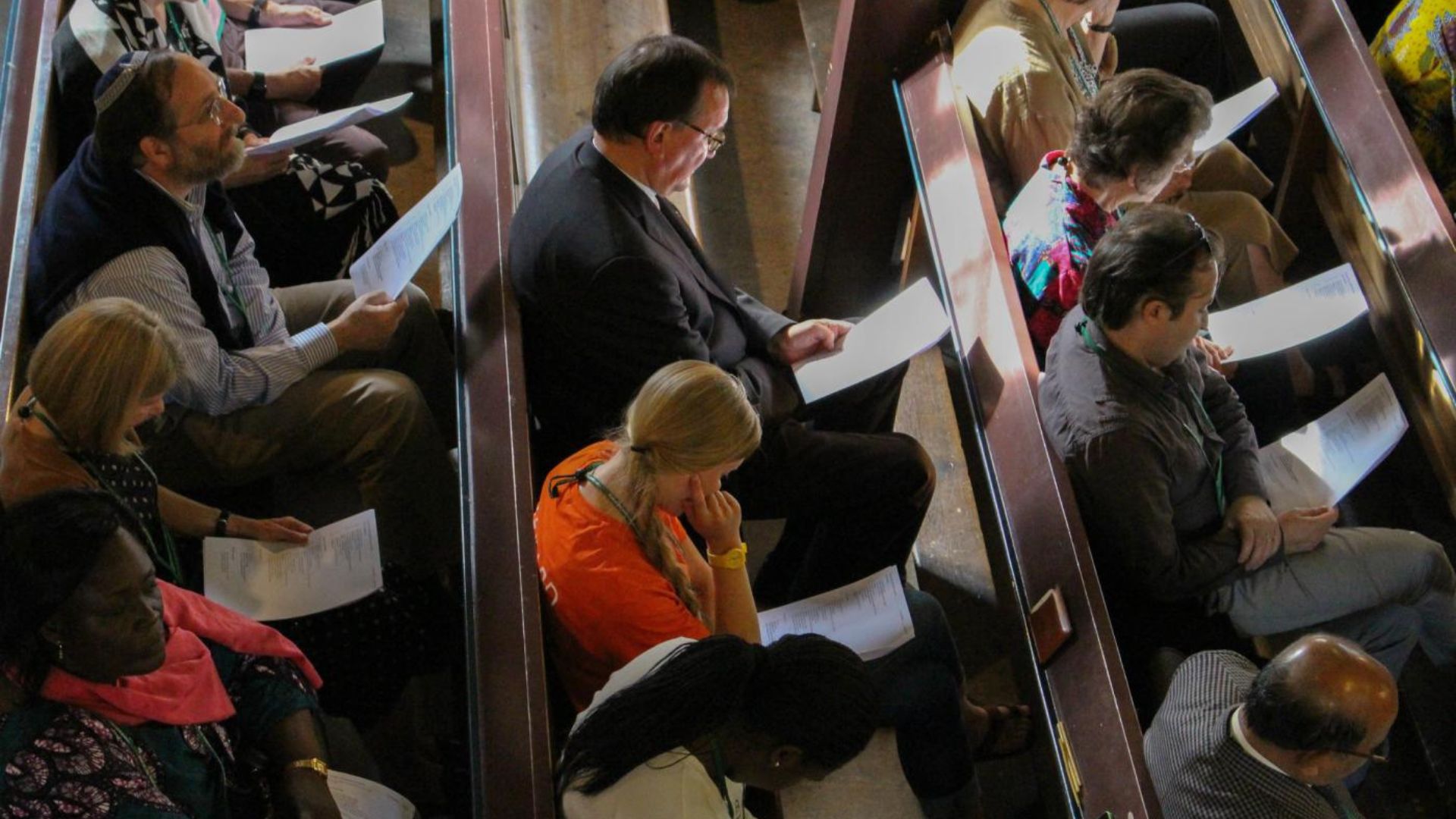 people sitting in a church reading papers showing the influence of religion on society