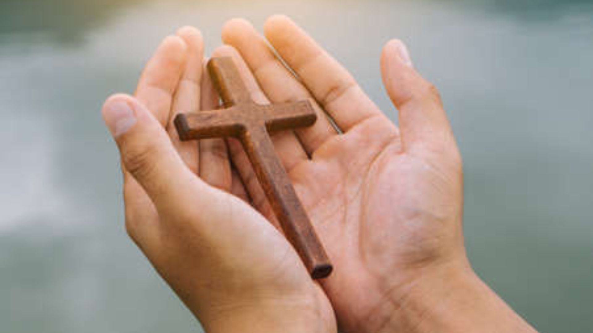 two hands holding a wood cross